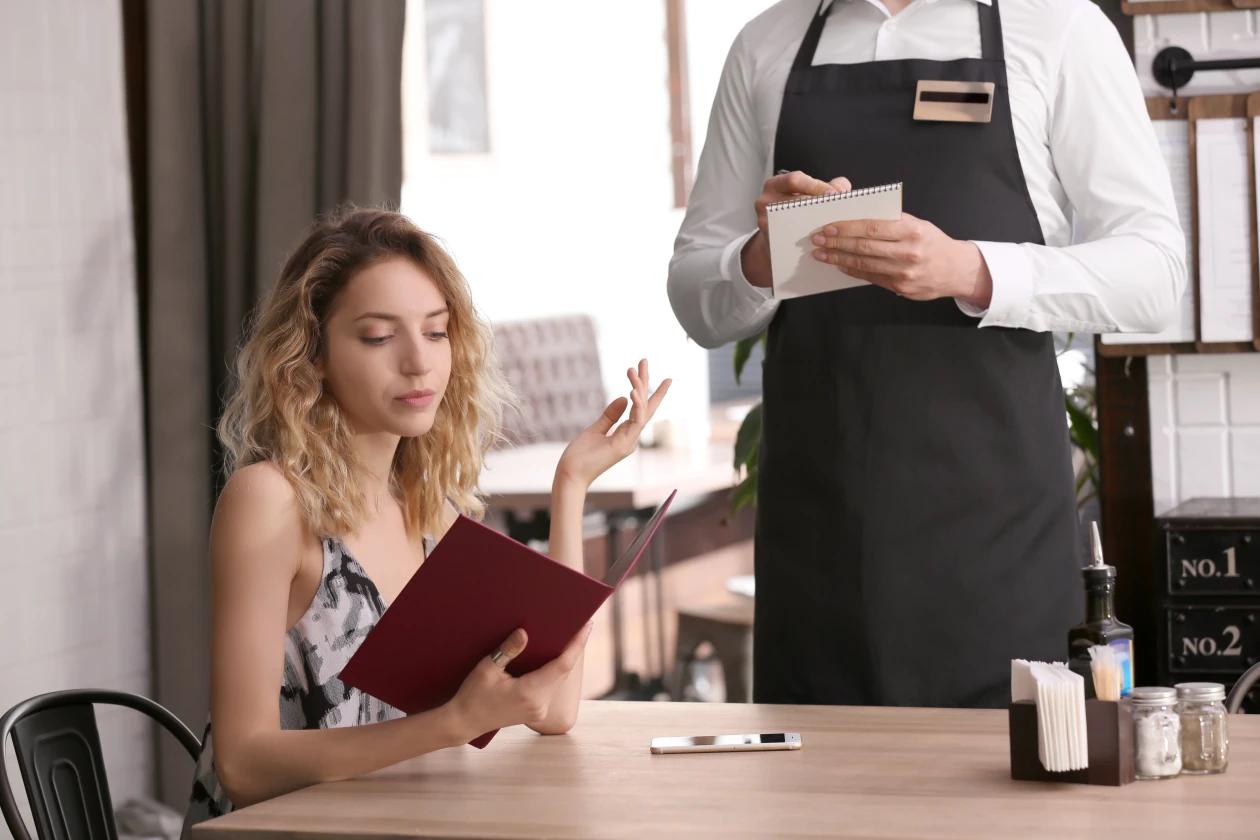 Mesero tomando el pedido de una clienta, ejemplo de buen servicio al cliente
